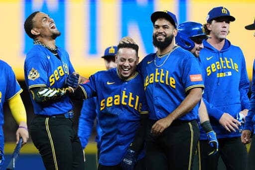 Seattle Mariners' Leo Rivas, center, celebrates with teammates Julio Rodríguez, left, and Seranthony Domínguez, third from left, after his walk-off RBI single in the 10th inning to win a baseball game against the Chicago Cubs, Friday, Aug. 21, 2026, in Seattle. (AP Photo/Lindsey Wasson) (AP Photo/Lindsey Wasson)