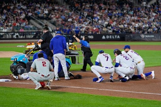 Players looks on as New York Mets first baseman Jared Young is helped bye medical personnel after colliding with pitcher Nolan McLean during the sixth inning of a baseball game against the Philadelphia Phillies, Thursday, Sept. 17, 2026, in New York. (AP Photo/Seth Wenig) (AP Photo/Seth Wenig)