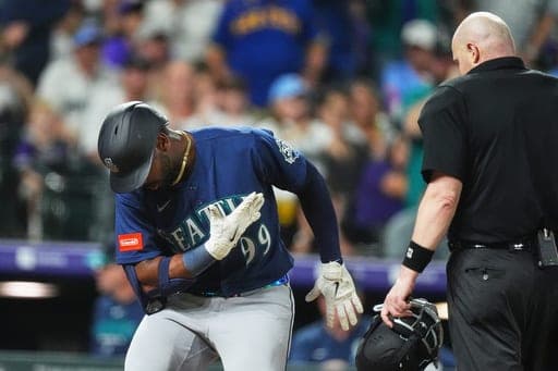 Seattle Mariners' Lazaro Montes, left, bows as he crosses home plate after hitting a solo home run off Colorado Rockies relief pitcher Jordan Romano as home plate umpire Mike Estabrook, right, looks on in the ninth inning of a baseball game Friday, Sept. 18, 2026, in Denver. (AP Photo/David Zalubowski) (AP Photo/David Zalubowski)