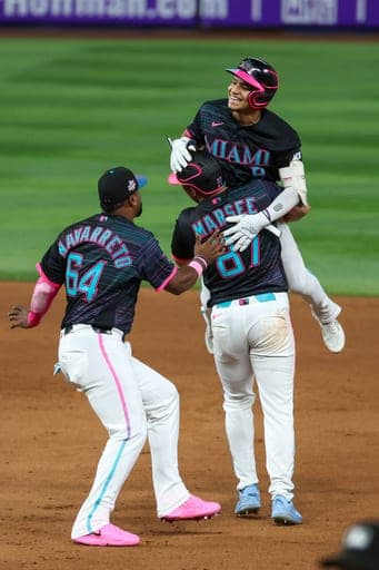 Miami Marlins' Javier Sanoja, top, celebrates with teammates Brian Navarreto (64) and Jakob Marsee (87) after hitting the winning RBI single during the ninth inning of a baseball game against the Washington Nationals, Friday, Aug. 21, 2026, in Miami. (AP Photo/David Santiago) (AP Photo/David Santiago)
