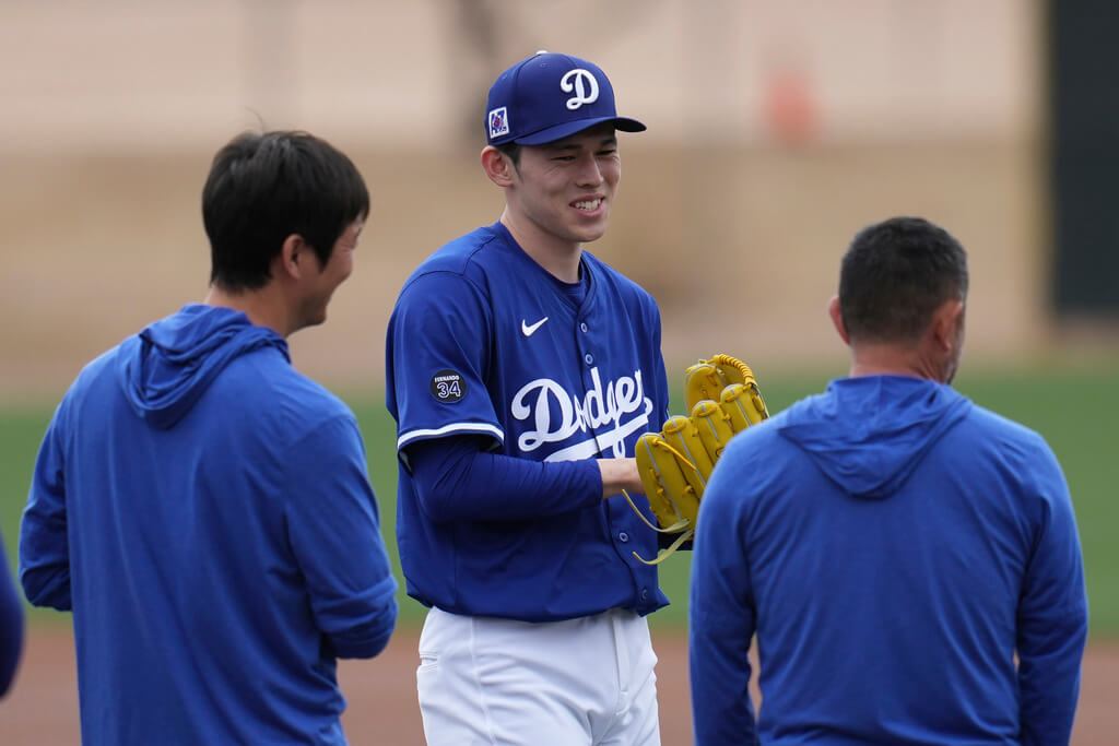 Los Angeles Dodgers pitcher Roki Sasaki, of Japan, smiles as he waits to warm up at the Dodgers baseball spring training facility, Wednesday, Feb. 12, 2025, in Phoenix. (AP Photo/Ross D. Franklin)