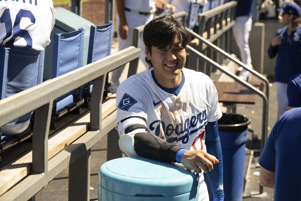Los Angeles Dodgers' Shohei Ohtani smiles in the dugout during a baseball game against the Arizona Diamondbacks in Los Angeles, Sunday, Aug. 31, 2025. (AP Photo/Kyusung Gong)
