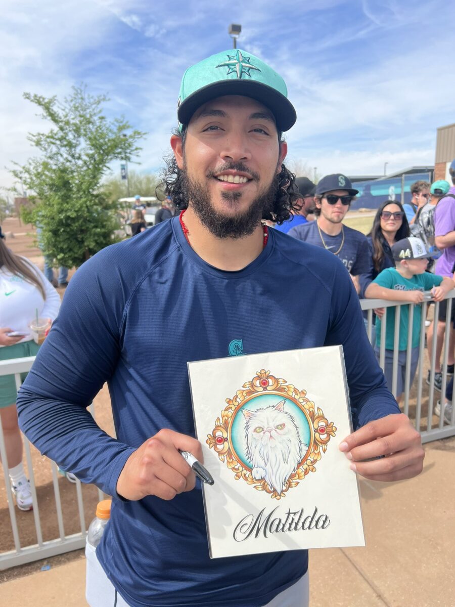 Seattle Mariners closer Andrés Muñoz smiles while holding a portrait of his Persian cat, Matilda, at spring training in Arizona.