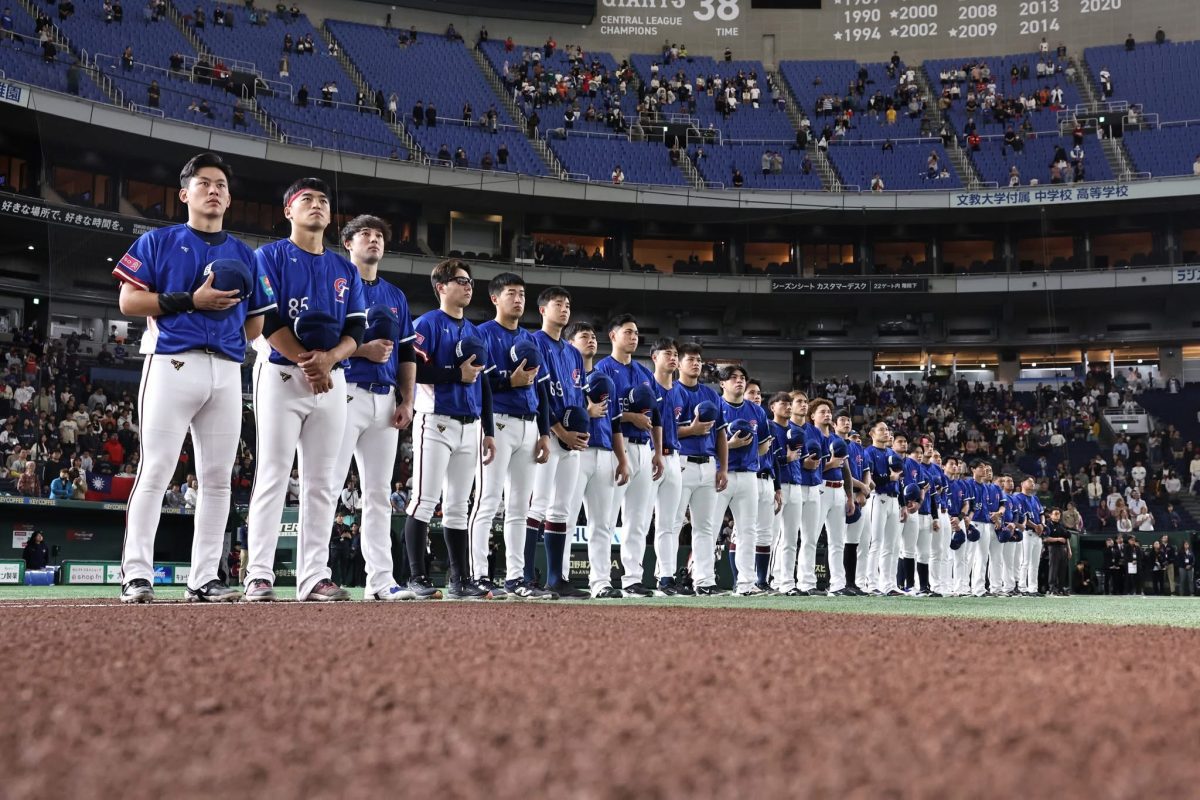 The Chinese Taipei national baseball team stands on the field in blue uniforms with hands over their hearts during the national anthem before a WBC Qualifier game.