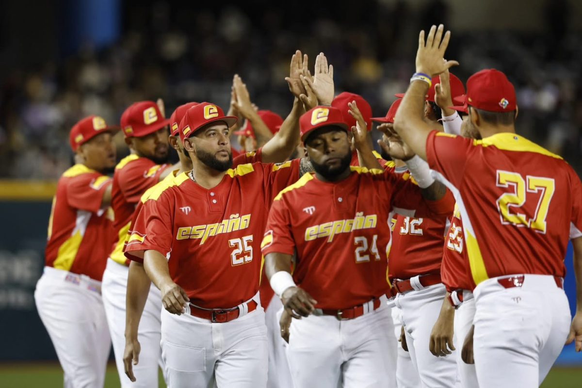 Spain's national baseball team celebrates a 12-5 victory over Chinese Taipei at the 2025 WBC Qualifiers in the Taipei Dome. Players high-five in red and yellow uniforms.