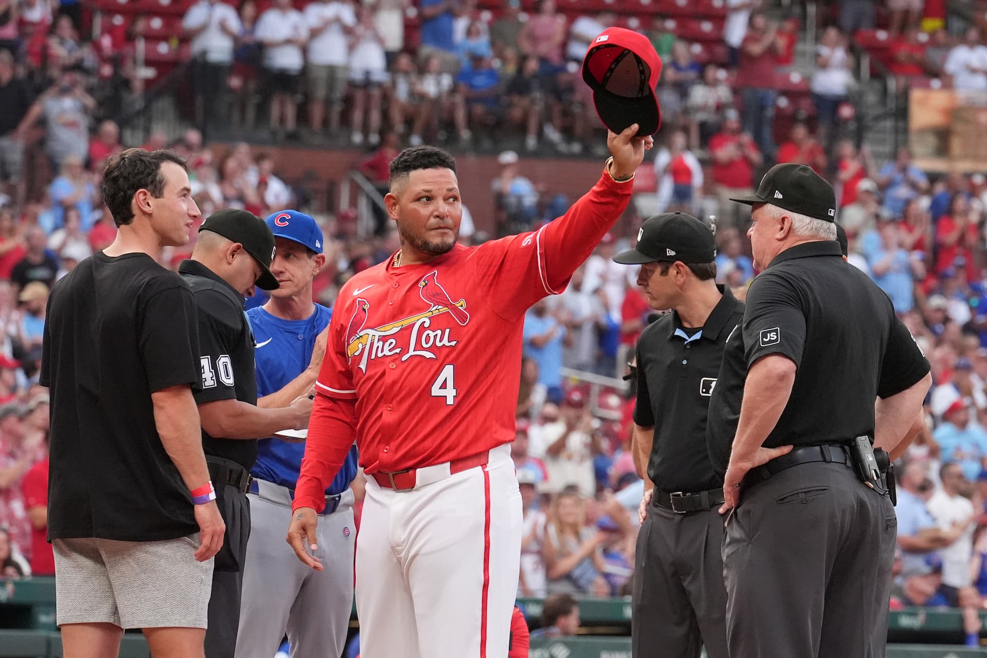 St. Louis Cardinals guest coach Yadier Molina tips his cap to cheering fans as he presents the lineup card before the start of a baseball game against the Chicago Cubs Friday, Aug. 8, 2025, in St. Louis. (AP Photo/Jeff Roberson)