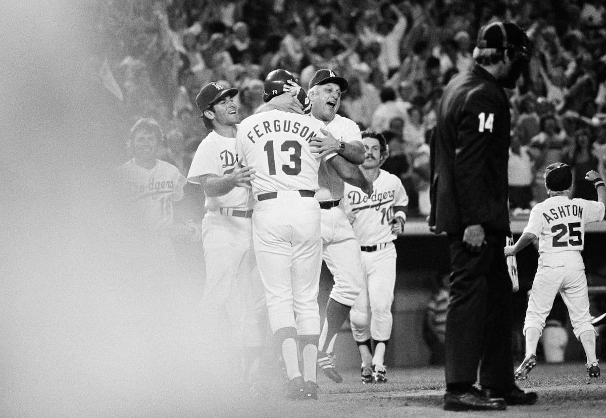 Title: Dodgers vs Giants MLB 1978 Image ID: 7808120617 Article: Los Angeles Dodgers manager Tommy Lasorda throws his arms around catcher Joe Fergus (13) as Steve Garvey, left, and Ron Cey, right, rush in to offer congratulations after Ferguson scored the winning run on a walk from third in the bottom of the ninth inning against the San Francisco Giants, Friday, Aug. 12, 1978, Los Angeles, Calif. Dodger Bill North was walked by Giants pitcher Randy Moffitt with the bases loaded, two out on a 3-and-1 pitch. The Dodgers take over sole possession of first place in the NL Western Division. (AP Photo/Lennox McLendon)
