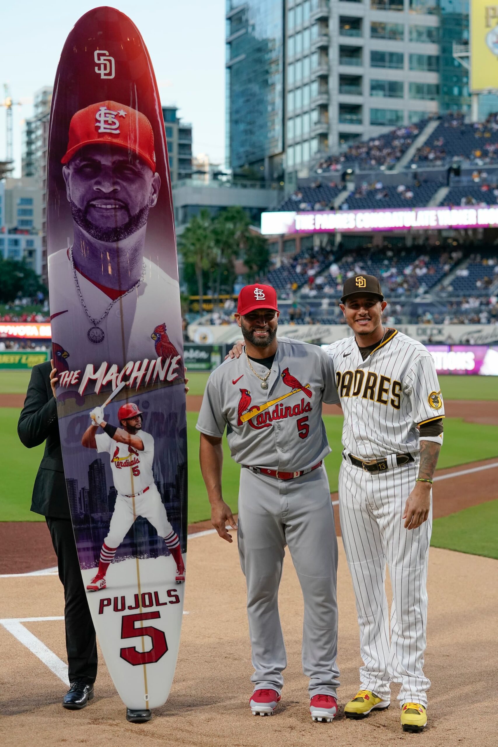 Title: Cardinals Padres Baseball Image ID: 22264083312200 Article: St. Louis Cardinals designated hitter Albert Pujols, left, stands with San Diego Padres third baseman Manny Machado after he was presented with a surfboard from the Padres to honor his future retirement before a baseball game, Tuesday, Sept. 20, 2022, in San Diego. (AP Photo/Gregory Bull)
