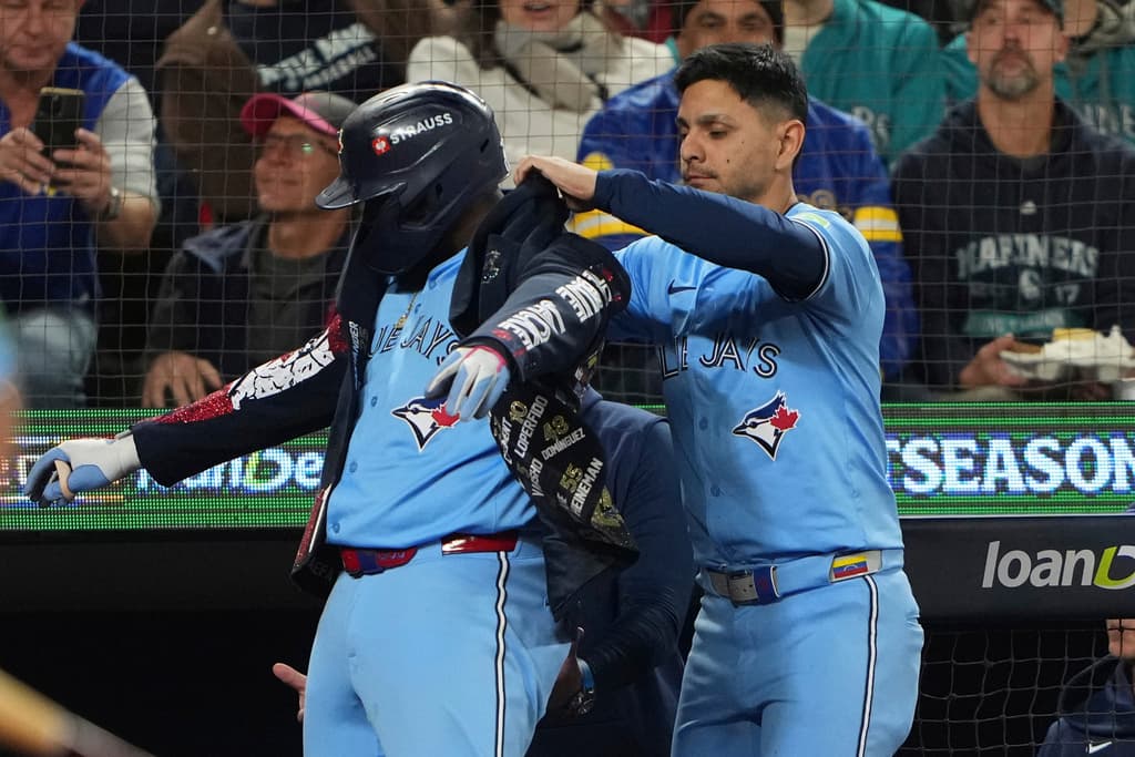 Title: ALCS Blue Jays Mariners Baseball Image ID: 25290107837816 Article: Toronto Blue Jays' Vladimir Guerrero Jr., left, puts on the celebratory postseason jacket after hitting a solo home run against the Seattle Mariners during the seventh inning in Game 4 of baseball's American League Championship Series, Thursday, Oct. 16, 2025, in Seattle. (AP Photo/Lindsey Wasson)