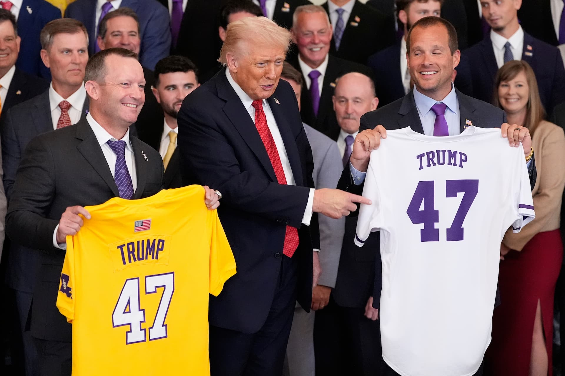 Title: Trump Image ID: 25293767925881 Article: President Donald Trump poses with the teams and LSU coach Jay Johnson, left, and LSU-Shreveport coach Brad Neffendor during an event to welcome the 2025 LSU and LSU-Shreveport national champion baseball teams in the East Room of the White House, Monday, Oct. 20, 2025, in Washington. (AP Photo/Alex Brandon)