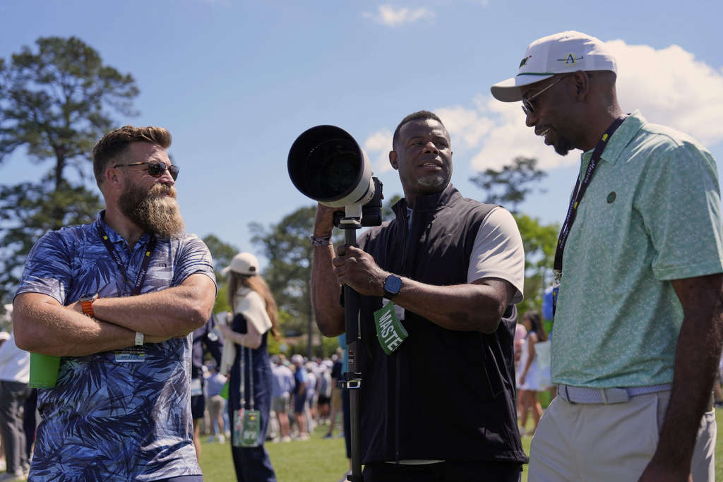 Title: Masters Golf Image ID: 25101636638123 Article: Former MLB great Ken Griffey Jr., center, and former NFL player Ryan Fitzpatrick, left, speak with a patron on the second hole during the second round at the Masters golf tournament, Friday, April 11, 2025, in Augusta, Ga. (AP Photo/Ashley Landis)