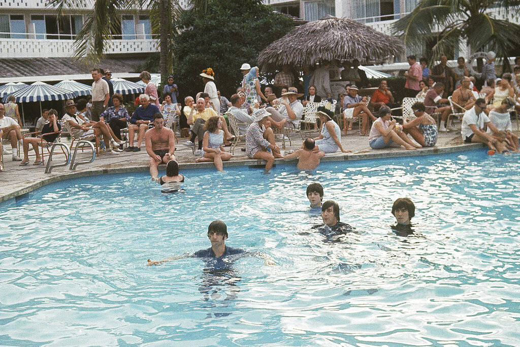 Title: The Beatles Image ID: 6502230243 Article: The Beatles surface during a dip in the swimming pool of the Nassau Beach Hotel in Nassau, Bahamas on Feb. 23, 1965, during the filming of a scene for their latest motion picture. The four jumped into the pool in jeans and dark blue shirts while a large audience of hotel guests watched from across the pool. From left to right are: Ringo Starr, Paul McCartney (rear) John Lennon and George Harrison. (AP Photo)