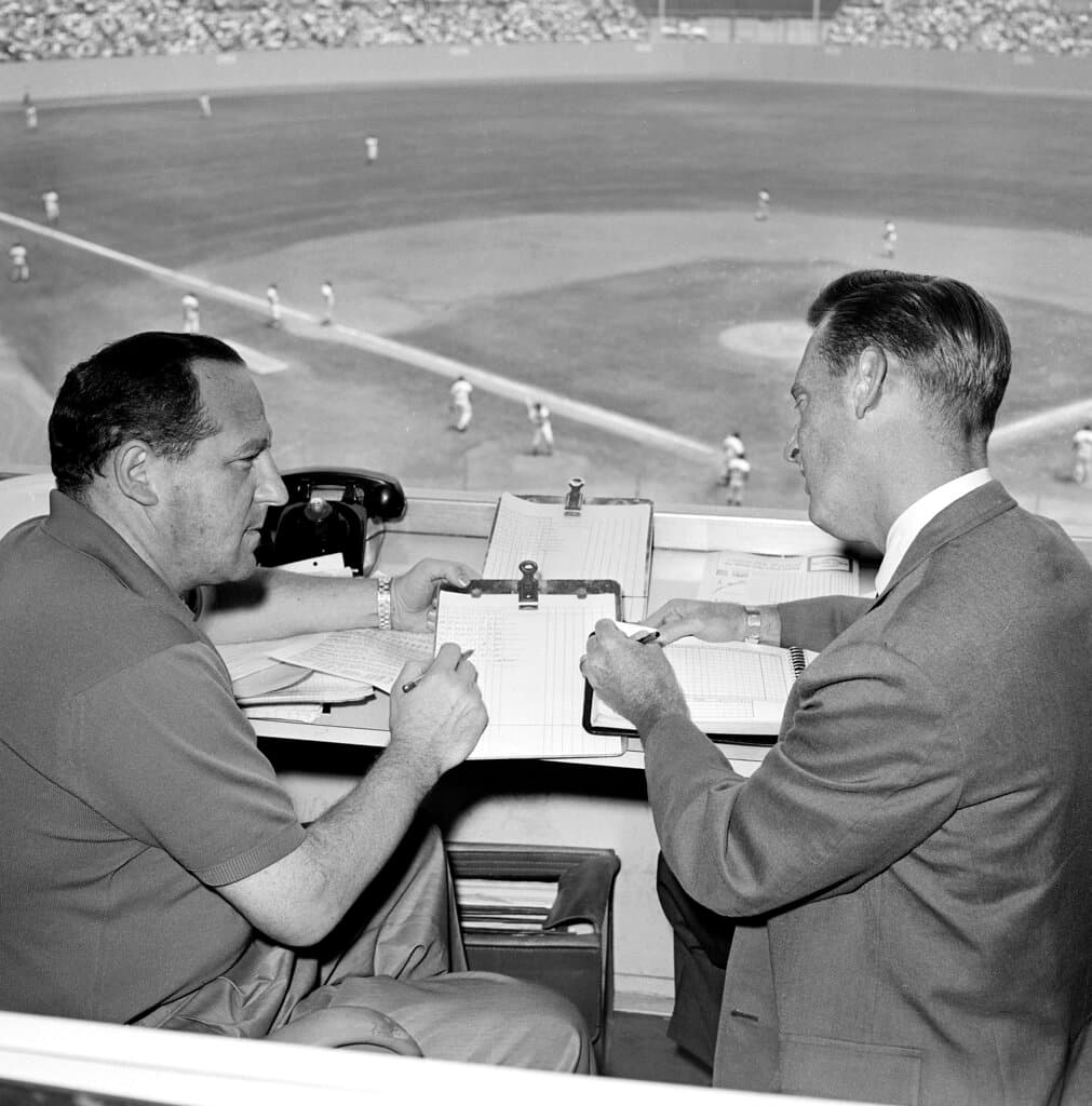 Title: Obit Vin Scully BaseballImage ID: 22215128901172 Article: FILE - Allan Roth, left, statistician of the Los Angeles Dodgers, sits in the booth with broadcaster Vin Scully in August 1963 in Los Angeles. Scully, whose dulcet tones provided the soundtrack of summer while entertaining and informing Dodgers fans in Brooklyn and Los Angeles for 67 years, died Tuesday night, Aug. 2, 2022, the team said. He was 94. (AP Photo/Harold Filan, File)
