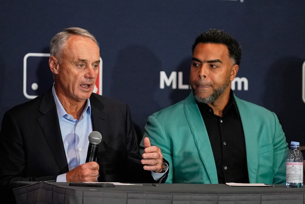 AP25342832942043 1 - World Baseball Network Title: Winter Meetings Baseball Image ID: 25342832942043 Article: Rob Manfred, left, commissioner of Major League Baseball answers questions during a news conference as Nelson Cruz, former baseball player and general manager of the Dominican National team listens during a news conference at the MLB winter meetings, Monday, Dec. 8, 2025, in Orlando, Fla. (AP Photo/John Raoux)