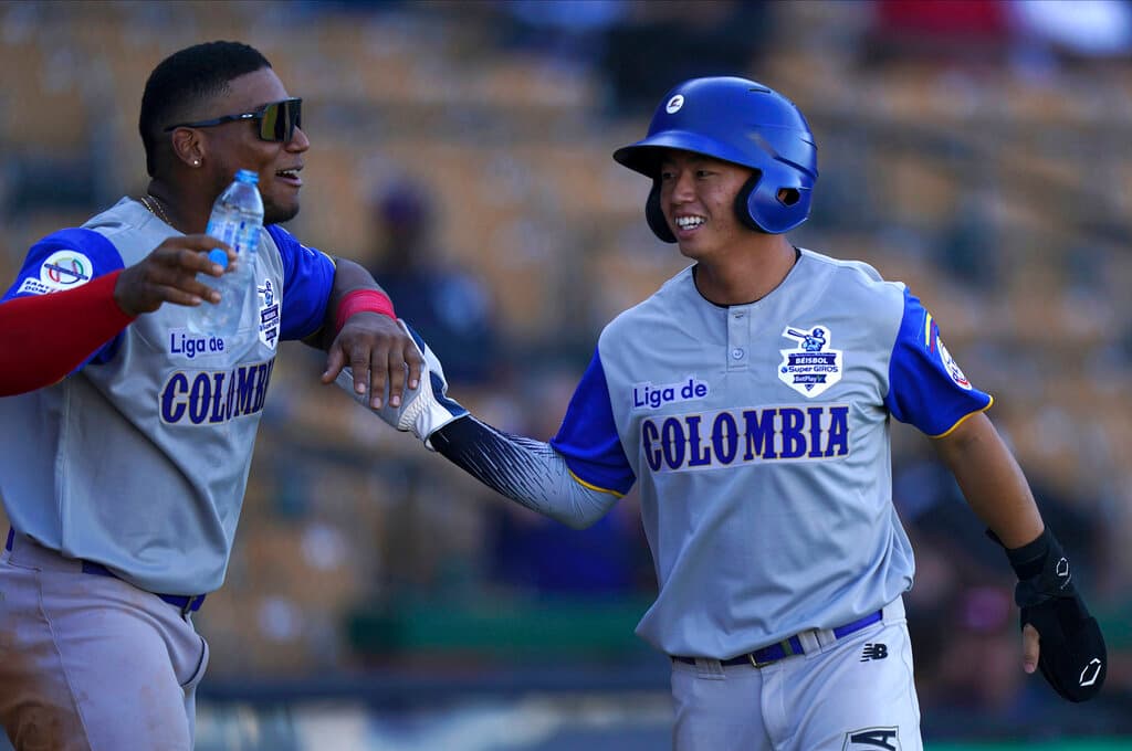 Title: Dominican Republic Caribbean Series Baseball Image ID: 22028777047697 Article: Colombia's baseman Tsung Che Cheng, right, is congratulated by a teammate after scoring a run against Venezuela during a Caribbean Series baseball game in Santo Domingo, Dominican Republic, Friday, Jan. 28, 2022. (AP Photo/Fernando Llano)