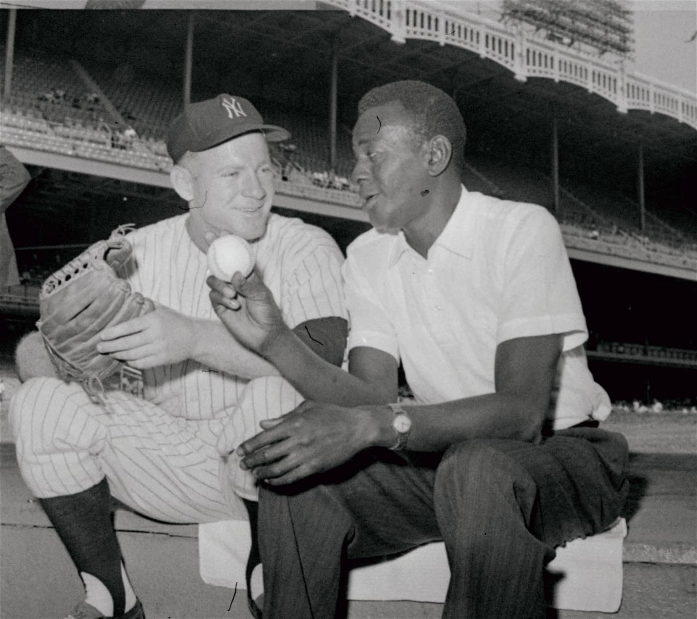Title: WHITEY FORD AND SATCHEL PAIGE Image ID: 610817045 Article: New York Yankee pitcher Whitey Ford, left, and Satchel Paige, star Negro League pitcher and former major leaguer, swap pitching talk on steps of the Yankee dugout in New York on August 17, 1961. Paige and Ford talked before the Yankee game with Chicago White Sox. Yanks won game, 5-3. (AP Photo)