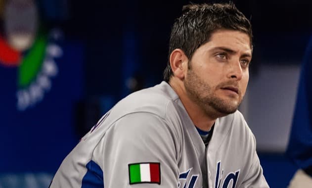 Italy national baseball team manager in the dugout wearing a jersey with the Italian flag patch during international play.